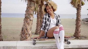Thoughtful young woman sitting on a skateboard video