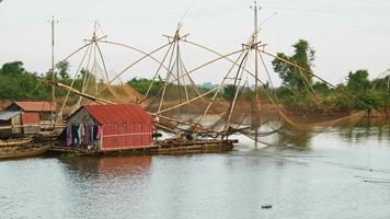 Pescador con una red de mano en casas flotantes con redes de pesca chinas