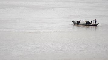 pescadores em um barco puxando uma rede de pesca na água atrás