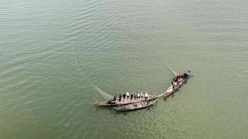 Pêcheurs dans de petits bateaux soulevant ensemble un grand filet hors de l'eau video