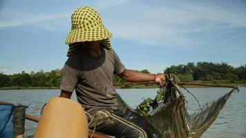 close up of prawn fisherman baiting net, dropping it deeper into a river and rowing boat for a new catch