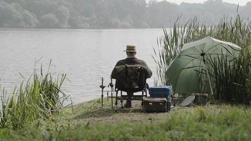 pensionista pescando nas margens de um lago inglês