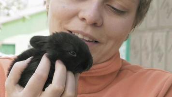 niña sostiene y mascotas pequeño bebé conejo negro