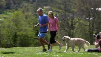casal maduro com cachorro correndo no campo, filmado em r3d