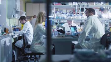 team av kaukasiska forskare i vita rockar arbetar i ett modernt laboratorium.