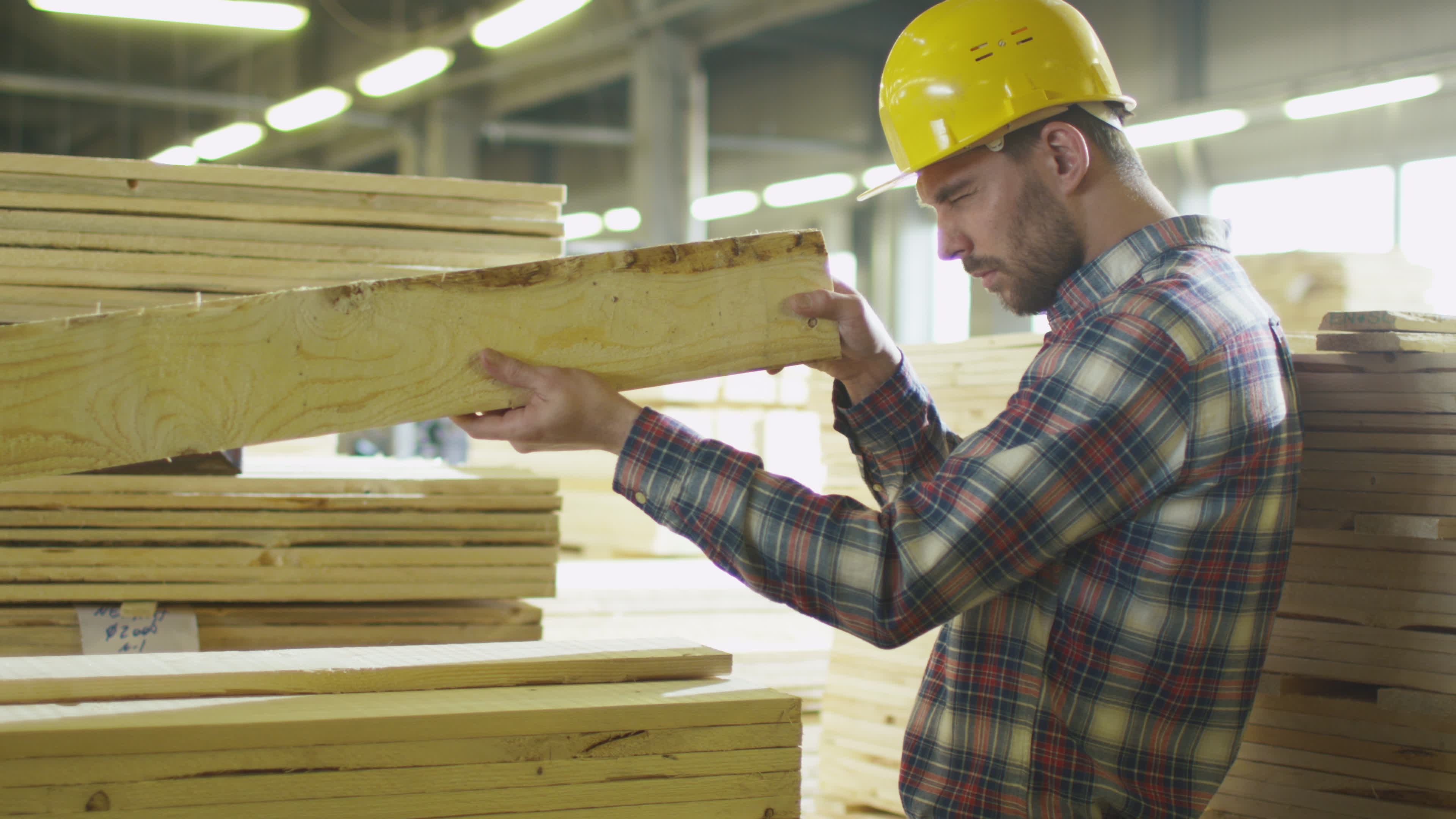 Lumber mill worker makes quality control of the wood in a warehouse