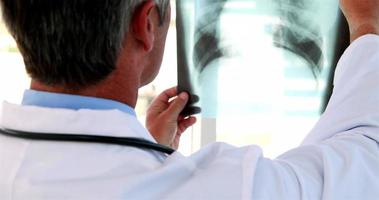 läkare som håller röntgen upp till fönstret