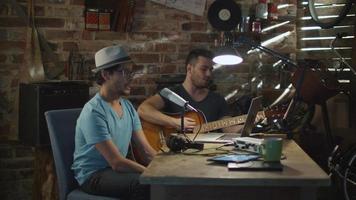 due giovani cantano e suonano la chitarra durante la registrazione di una canzone in un home studio in un garage. video