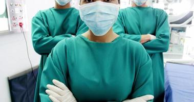 porträtt av kirurger och sjuksköterska som står med armarna korsade i operationsrummet