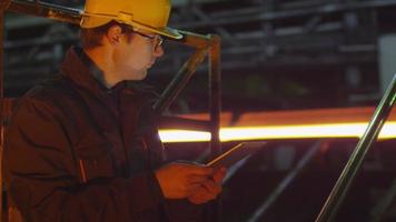 Ingenieur im Schutzhelm mit Tablet-PC in der Gießerei. industrielles Umfeld.