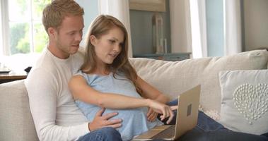 casal com mulher grávida usando laptop filmado em r3d video