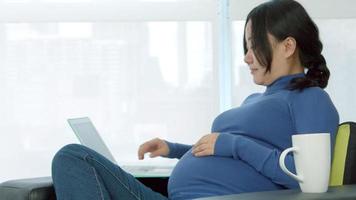 asiatische schwangere Frau, die in einem Sofa sitzt