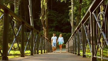cara e uma garota andando em uma ponte no parque.