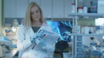 kvinna forskare går med dokument i ett laboratorium där kollegor arbetar.