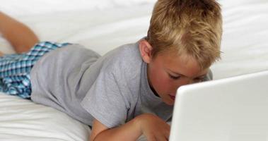garotinho usando laptop na cama