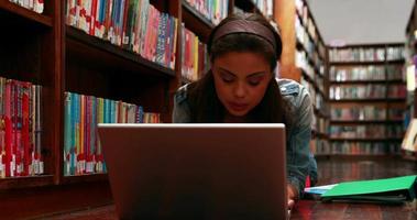 Student, der auf Boden in der Bibliothek mit Laptop liegt video