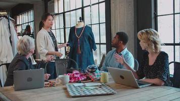 cuatro diseñadores de moda reunidos discutiendo prendas
