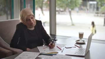 mulher do Oriente Médio colorindo páginas em um café video