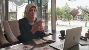 Señora de negocios de Oriente Medio haciendo llamadas telefónicas en el café video