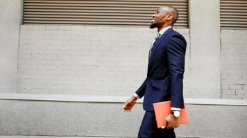 uomo d'affari afroamericano a piedi con tablet all'aperto