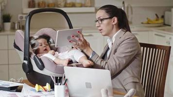 werkende moeder vermakelijke baby met tabletcomputer video