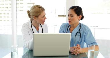arts en verpleegster die een dossier op laptop doornemen