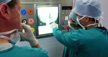 cirurgiões e enfermeira olhando um raio-x