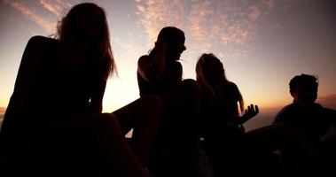 Teens sitting on rocks together at dusk video