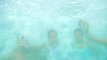 família hispânica pula em uma piscina junta