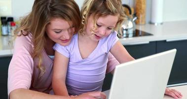 mor och dotter använder laptop tillsammans