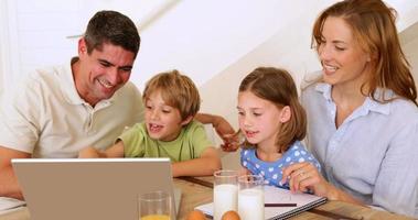 glückliche Familie mit Laptop zusammen am Frühstückstisch video