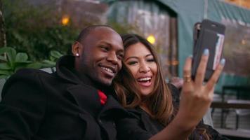 ett par som sitter på en parkbänk och tar selfies video