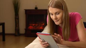 mooie aantrekkelijke jonge vrouw tabletcomputer liggend op de bank. surfen op internet en glimlachen