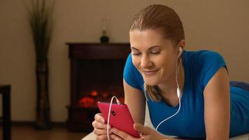 mooie aantrekkelijke jonge vrouw met smartphone liggend op de bank en luisteren naar de muziek