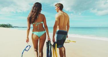 casal com equipamento de snorkel na praia