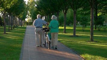 äldre par som går med cykeln.