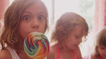 A little girl eating a lollypop and then eating cookie dough with her sisters