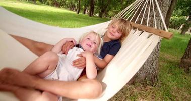 Mischievous siblings having fun on a hammock at park video