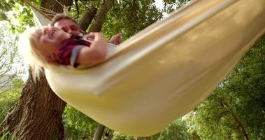 Lovely dad hugs his blond child on a hammock