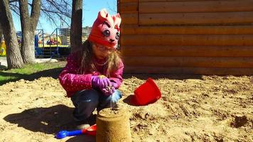 kind meisje spelen in de zandbak. meisje poseren taart uit het zand. video