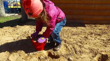 barnflicka som leker i sandlådan. flicka poserar tårta ur sanden. video