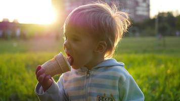 het kind eet het ijs bij zonsondergang video