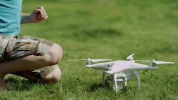 Kind, das moderne Drohne auf dem grünen Rasen zusammenbaut. Propeller aufsetzen
