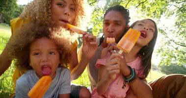 Jeune couple attrayant, manger des glaces au soleil avec des enfants