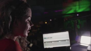 DJ-Mädchen im roten Kleid, das am Plattenteller auf der Party im Nachtclub dreht. Hände heben video