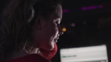 Dj girl in headphones spinning at turntable on party in nightclub. Spotlights video