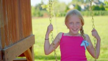 Young blonde girl swinging outside