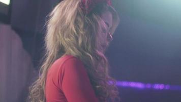 DJ-Mädchen im roten Kleid dreht sich am Plattenteller im Nachtclub. Künstler. tanzen. jubeln