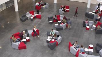 Wide overhead shot of students in a busy university lobby, shot on R3D