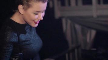 attraktives DJ-Mädchen in schwarzem Top wedelt mit den Hüften, singt am Plattenteller im Nachtclub